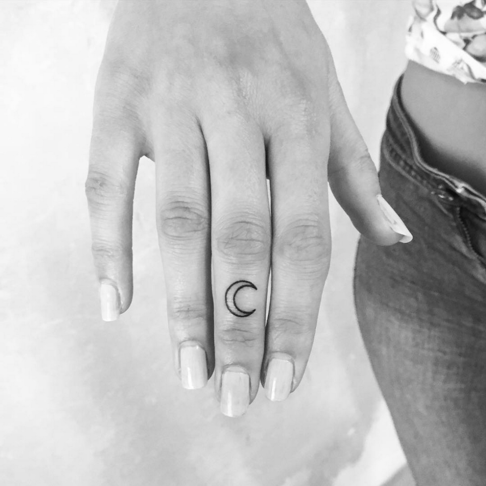 Minimalist white cross tattoo on the finger.